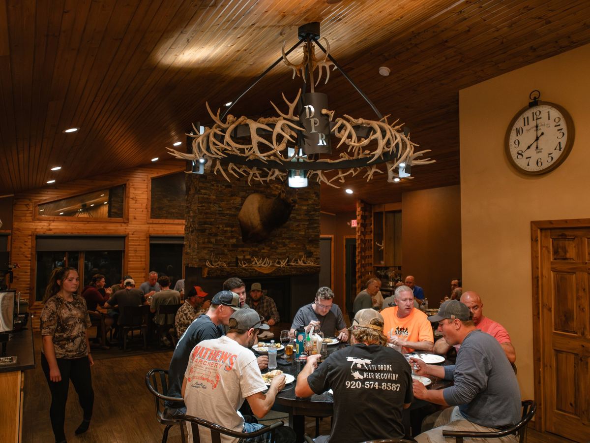 Hunters at dinner under the DPR antler chandelier in the Double P Ranch lodge dining room