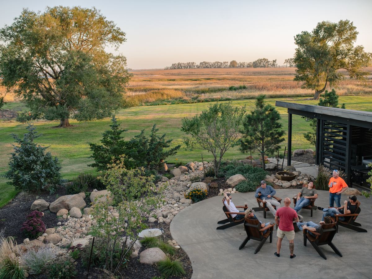 Hunters relaxing around the fire pit on the Double P Ranch lodge patio overlooking prairie wetlands in Clark, South Dakota