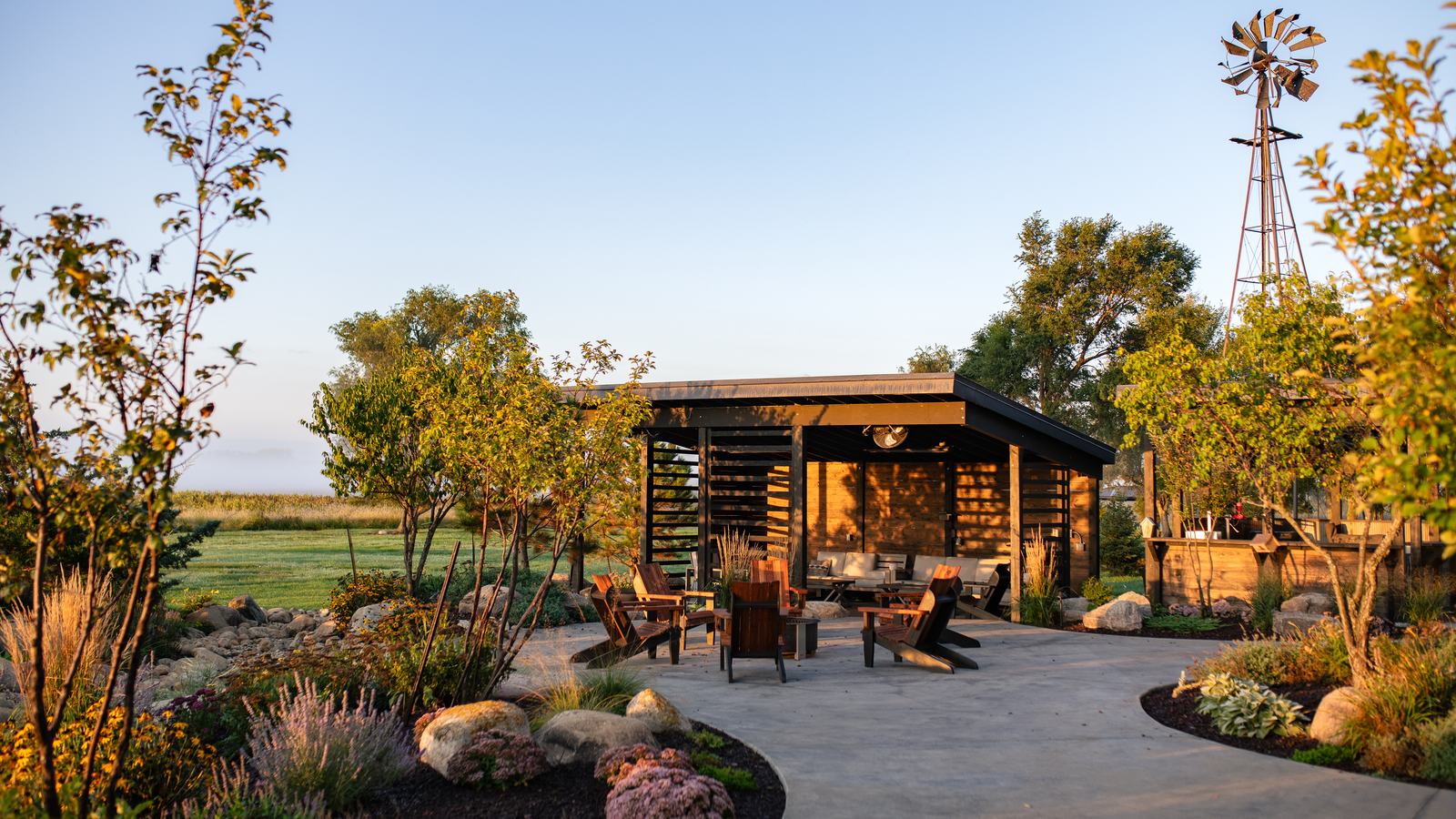 Outdoor pavilion, fire pit seating and windmill at golden hour on the Double P Ranch lodge grounds